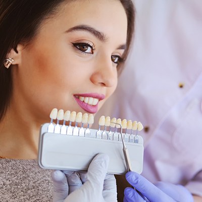 Woman comparing shades of veneers with a dentist